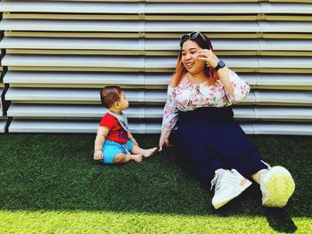 Smiling mother sitting with son against metal structure