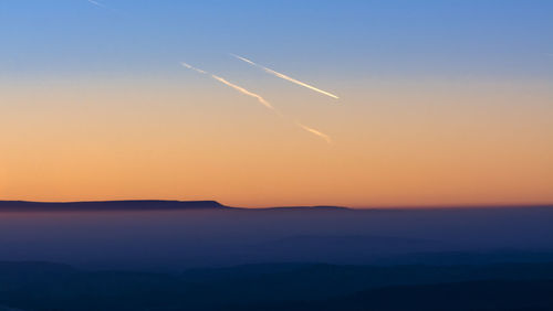 Scenic view of vapor trails in sky during sunset