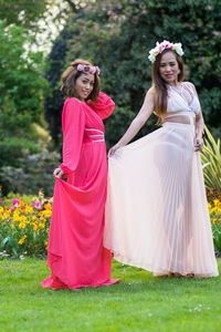 Portrait of young women holding dress while standing at public park