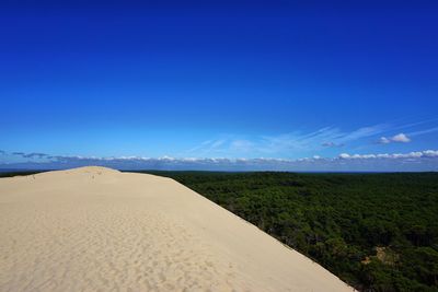 Scenic view of desert land against blue sky