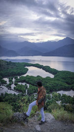 Full length of man looking away while standing against lake