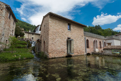 Buildings by river against sky