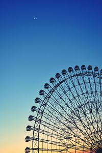 Low angle view of ferris wheel against clear blue sky at dusk