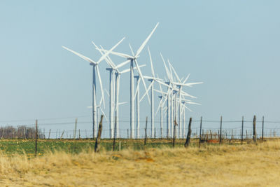 Wind turbines on field against clear sky