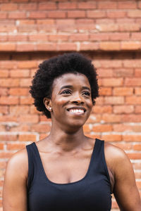 Portrait of smiling young man against brick wall