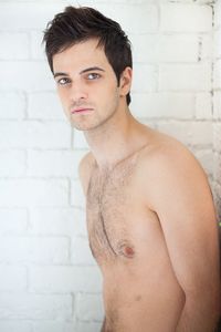 Portrait of shirtless man standing against wall