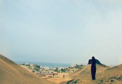 Rear view of woman wearing angel costume at desert against sky