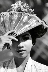 Close-up of woman looking away while shielding with hand fan