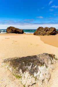 Scenic view of rocks on beach against blue sky