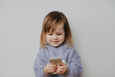 Portrait of young woman using mobile phone against white background