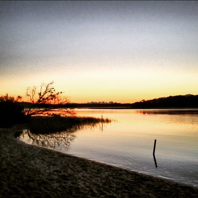 water, tranquil scene, silhouette, tranquility, sunset, scenics, lake, beauty in nature, nature, reflection, sky, tree, idyllic, one person, one animal, bird, outdoors, dusk, non-urban scene, standing