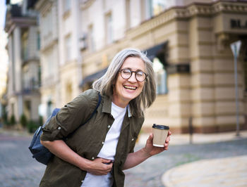 Portrait of young woman using mobile phone in city