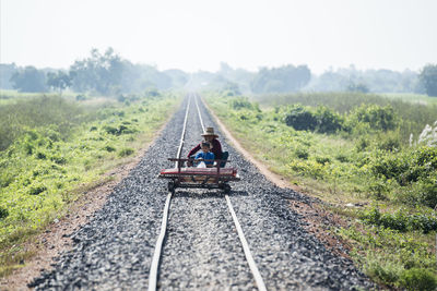 Rear view of people sitting on railroad track