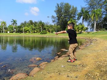 Full length of boy on water in park against sky