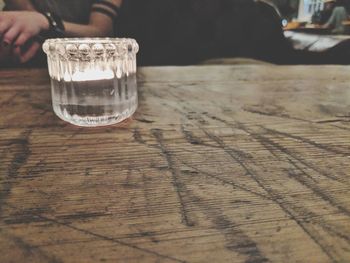 Low section of person holding glass of water on table