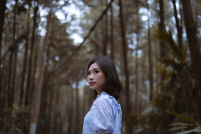 Side view of woman looking away in forest