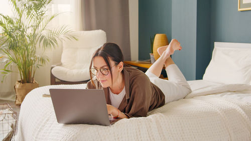 Young woman using laptop on bed at home