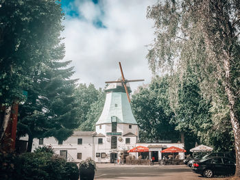 Traditional windmill by building against sky