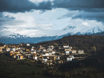 Aerial view of townscape by mountain against sky