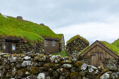 Houses on rock by building against sky