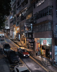 Cars on road by buildings in city at night