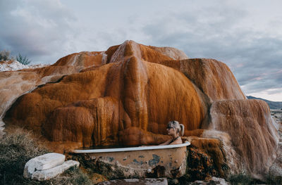 Woman sitting in bathtub at mystic hot springs during sunset