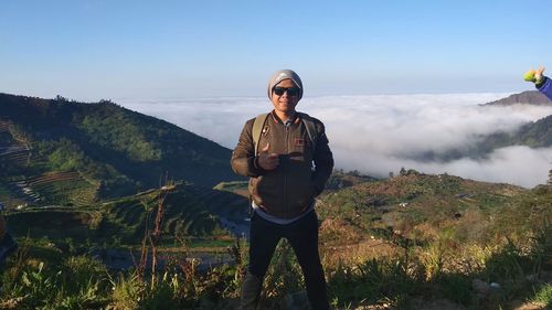 Young man standing on mountain against sky