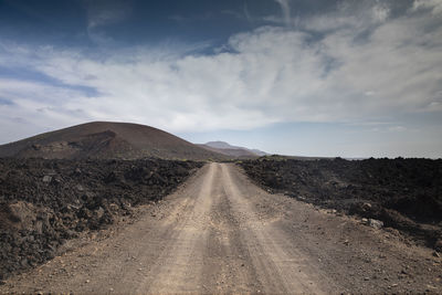 Road amidst land against sky