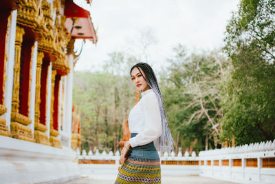 Side view of woman standing against built structure