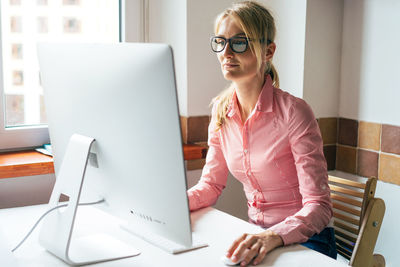 Business young pretty woman in glasses works on the computer.