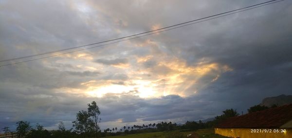 Low angle view of trees and buildings against sky during sunset