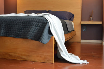 Bed base, bedroom with mat on the floor, clay pot in the background, wooden credenza and mirror.