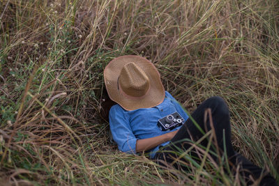 High angle view of woman with hat covering face lying on grass