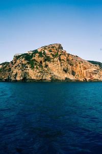 Scenic view of sea and mountains against clear blue sky