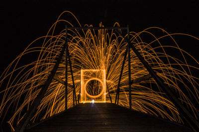 Illuminated wire wool spinning on bridge at night