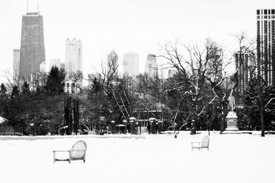 Snow covered trees and buildings against sky