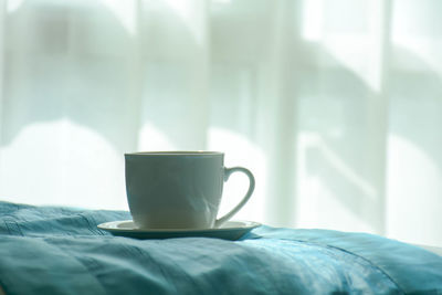 Close-up of coffee cup on bed
