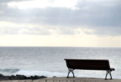 Chair on beach against sky