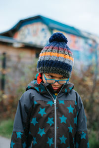 Cute boy wearing knit hat standing outdoors during winter