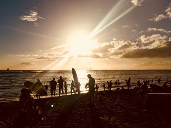 People on beach against sky during sunset