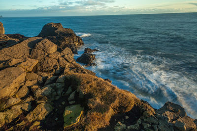 Scenic view of rocks on beach against sky