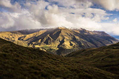 Scenic view of mountain range against cloudy sky