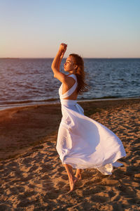 Woman wearing sunglasses at beach during sunset