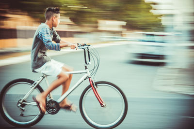 Blurred motion of boy riding bicycle on road