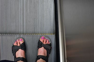 Low section of woman standing on metal grate