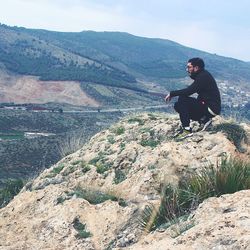 Man looking at view while sitting on mountain