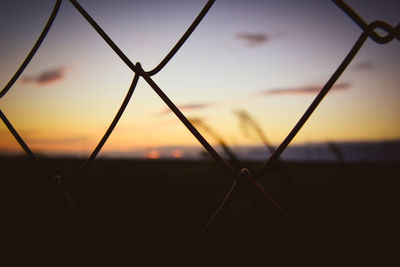 Close-up of silhouette fence against sunset sky