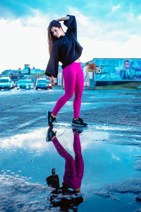 Full length portrait of woman standing by pink against sky