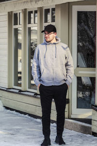 Man wearing cap standing in snow outdoors