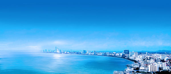 View of sea and buildings against blue sky